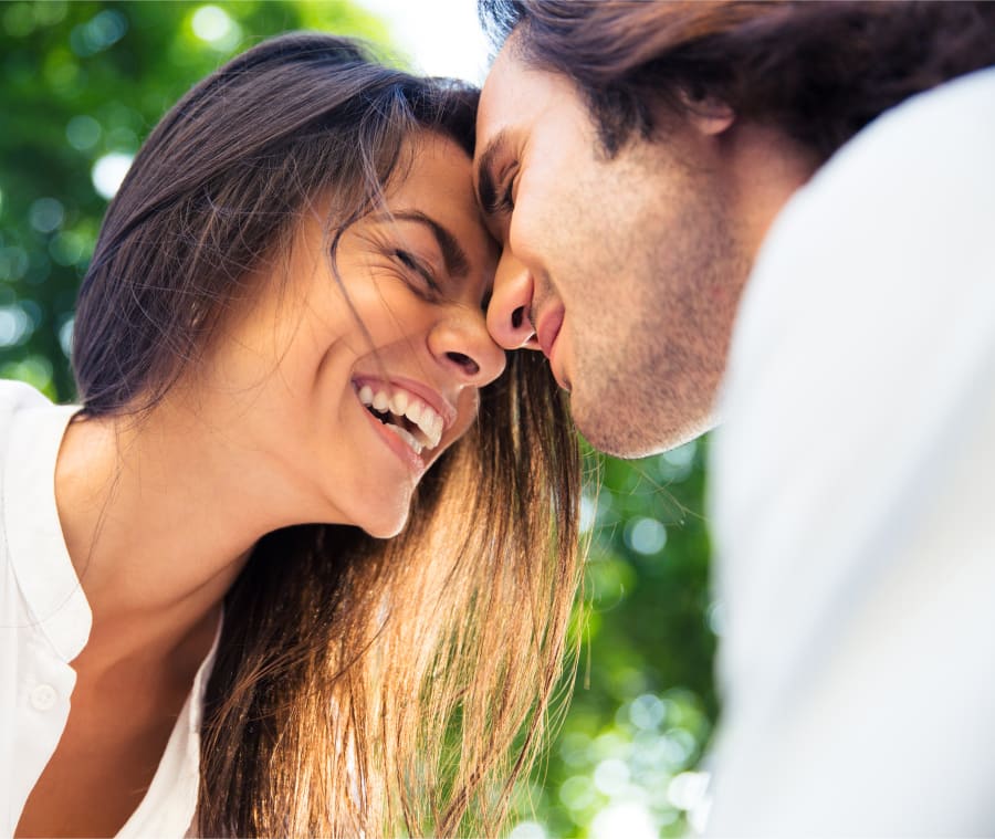 Woman and man smiling as they rest their foreheads together.