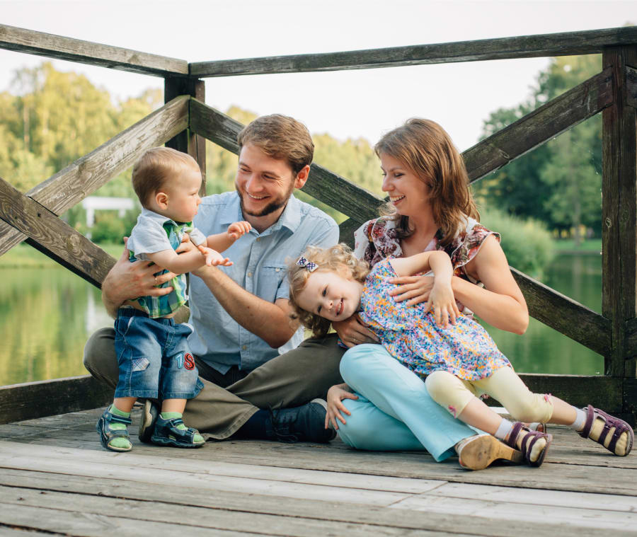 Family of four sitting together on a lakeside deck, enjoying time by the water.