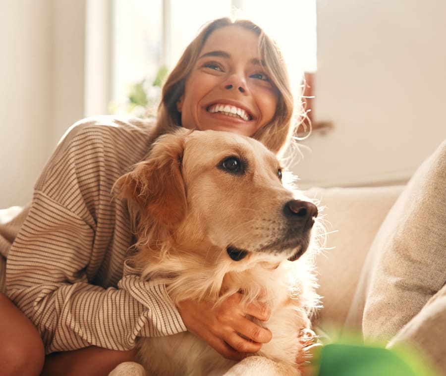 Woman smiling while holding her Golden Retriever.