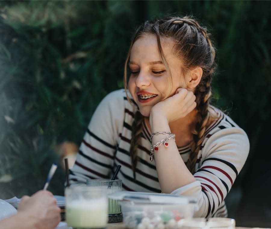 Young girl smiling and wearing braces while studying.