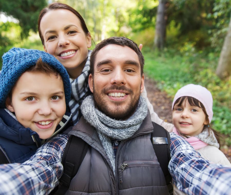 Family of four walking together outdoors, smiling and enjoying time with one another.