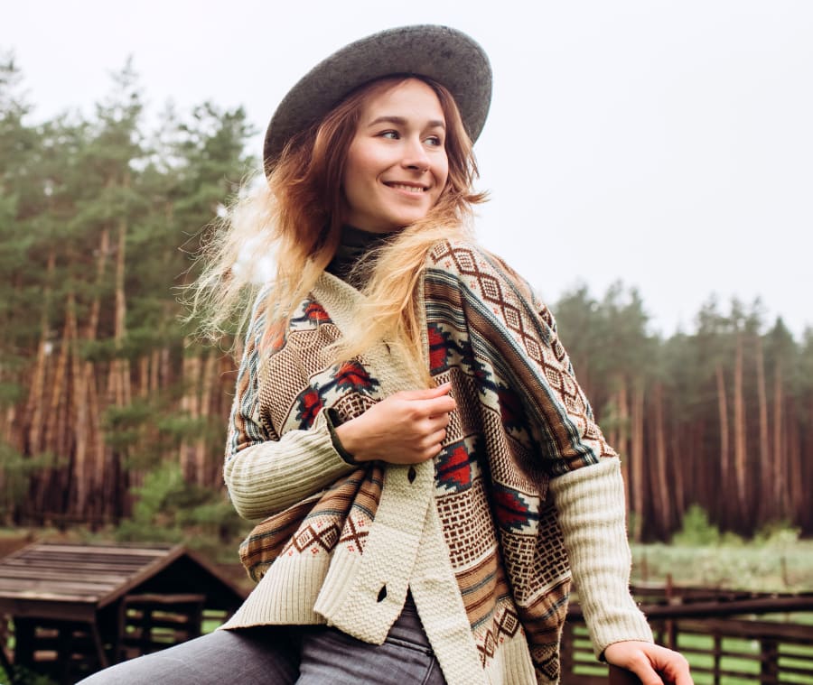 Cowgirl sitting on a fence on a ranch.